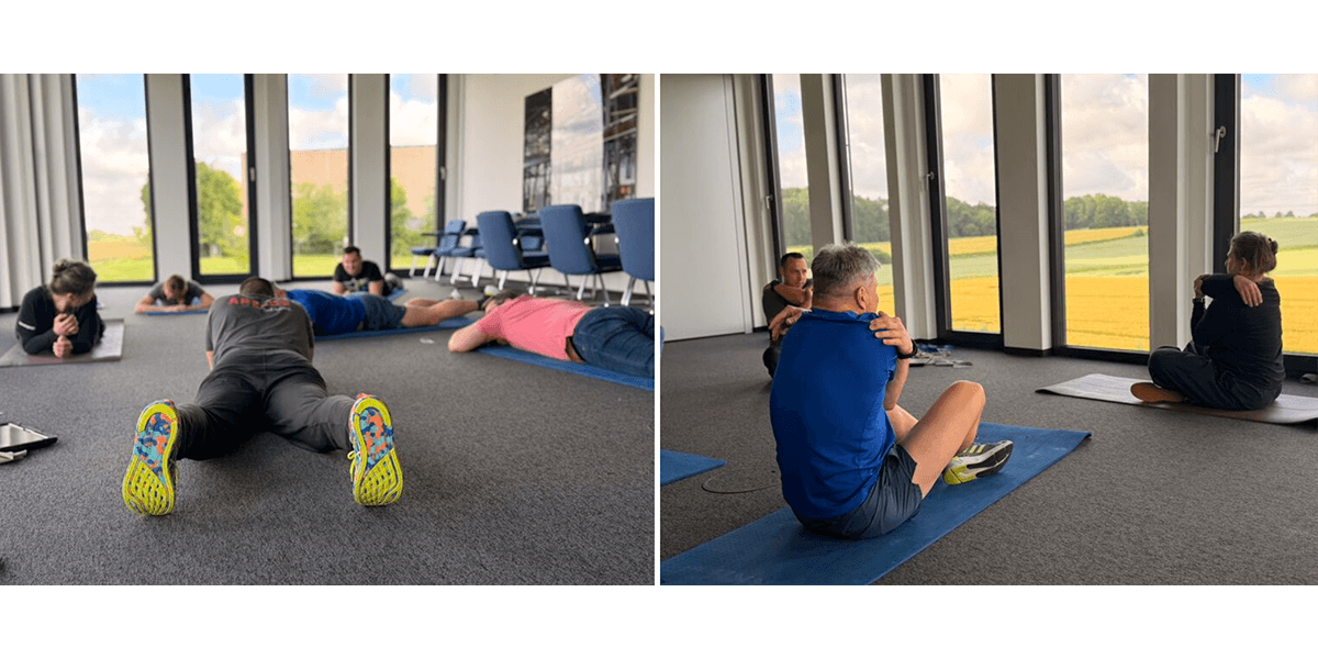 Dans une salle lumineuse dotée de grandes fenêtres, plusieurs participants effectuent des exercices pour le dos sur des tapis, notamment des exercices d'étirement et de renforcement en position couchée sur le ventre et assise.